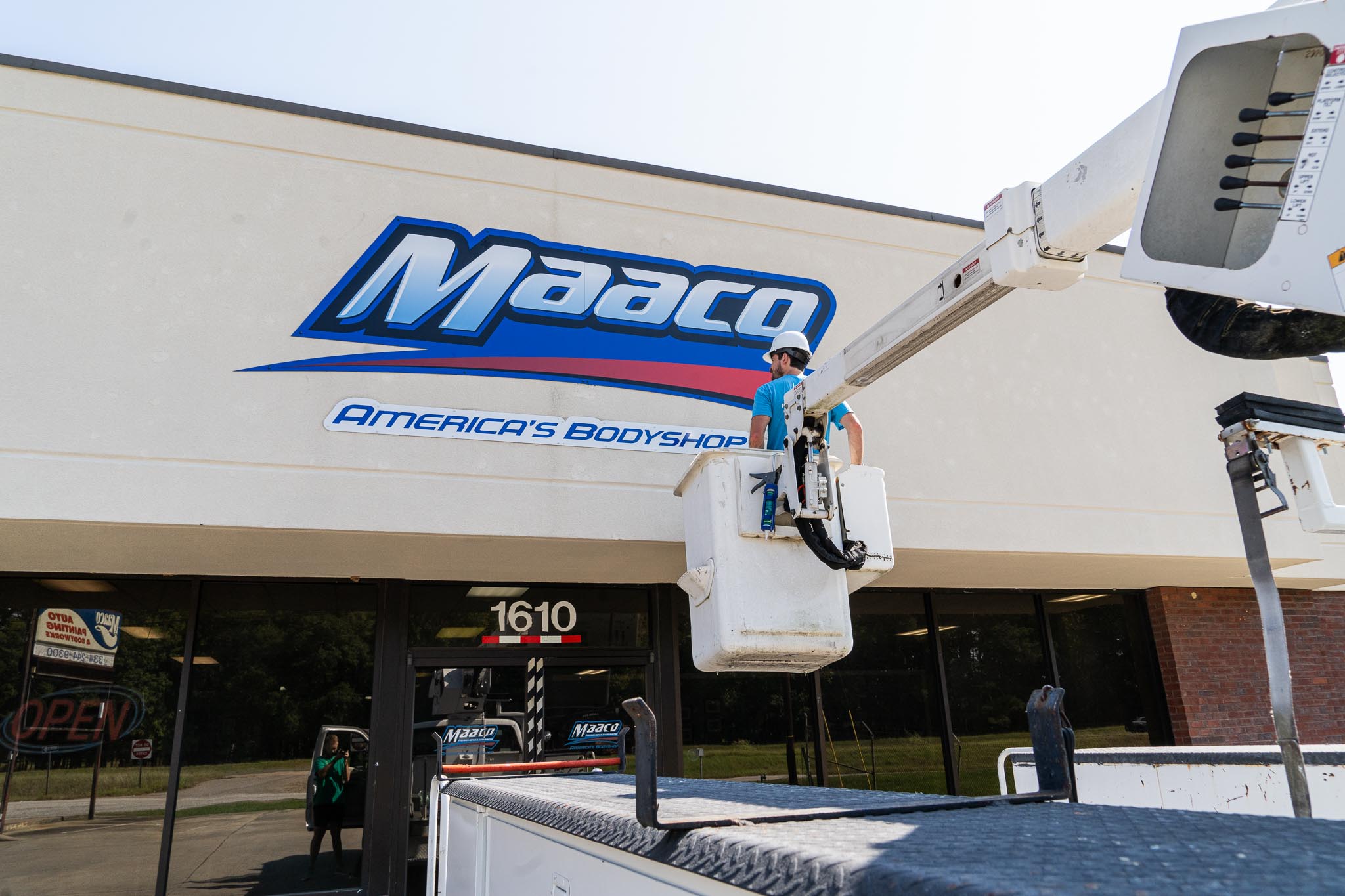 A man in a bucket truck installing an outdoor sign