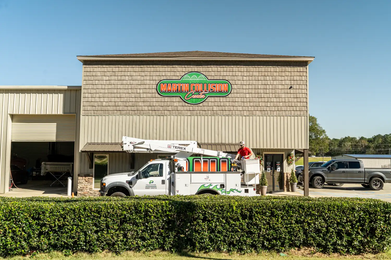 Man in bucket truck looking at building with a green and orange sign on it