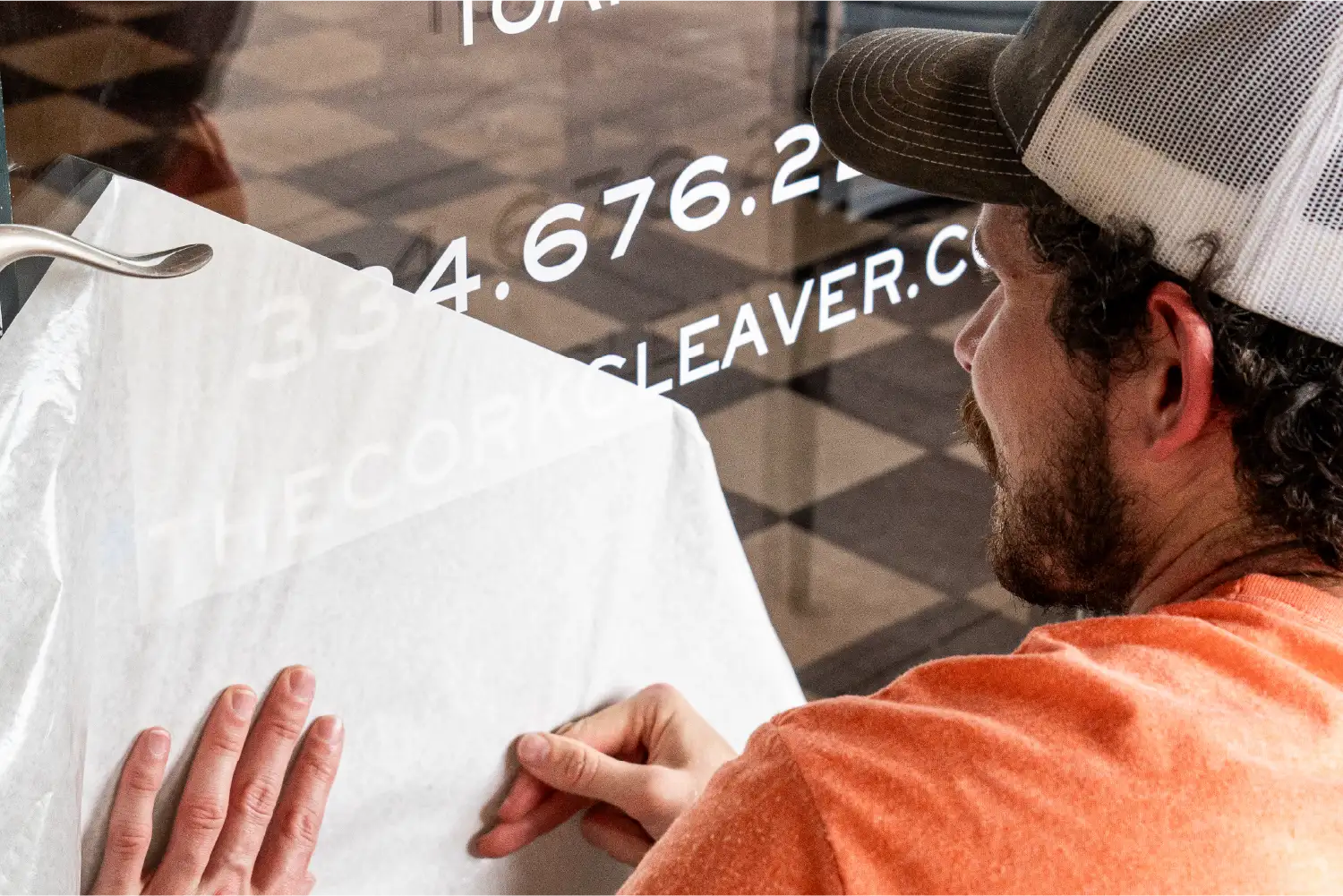 Man applying & installing white decals on a glass door