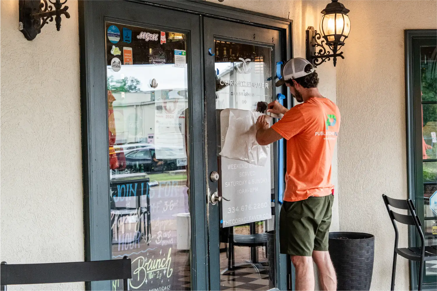 Man installing & applying white decals on glass doors