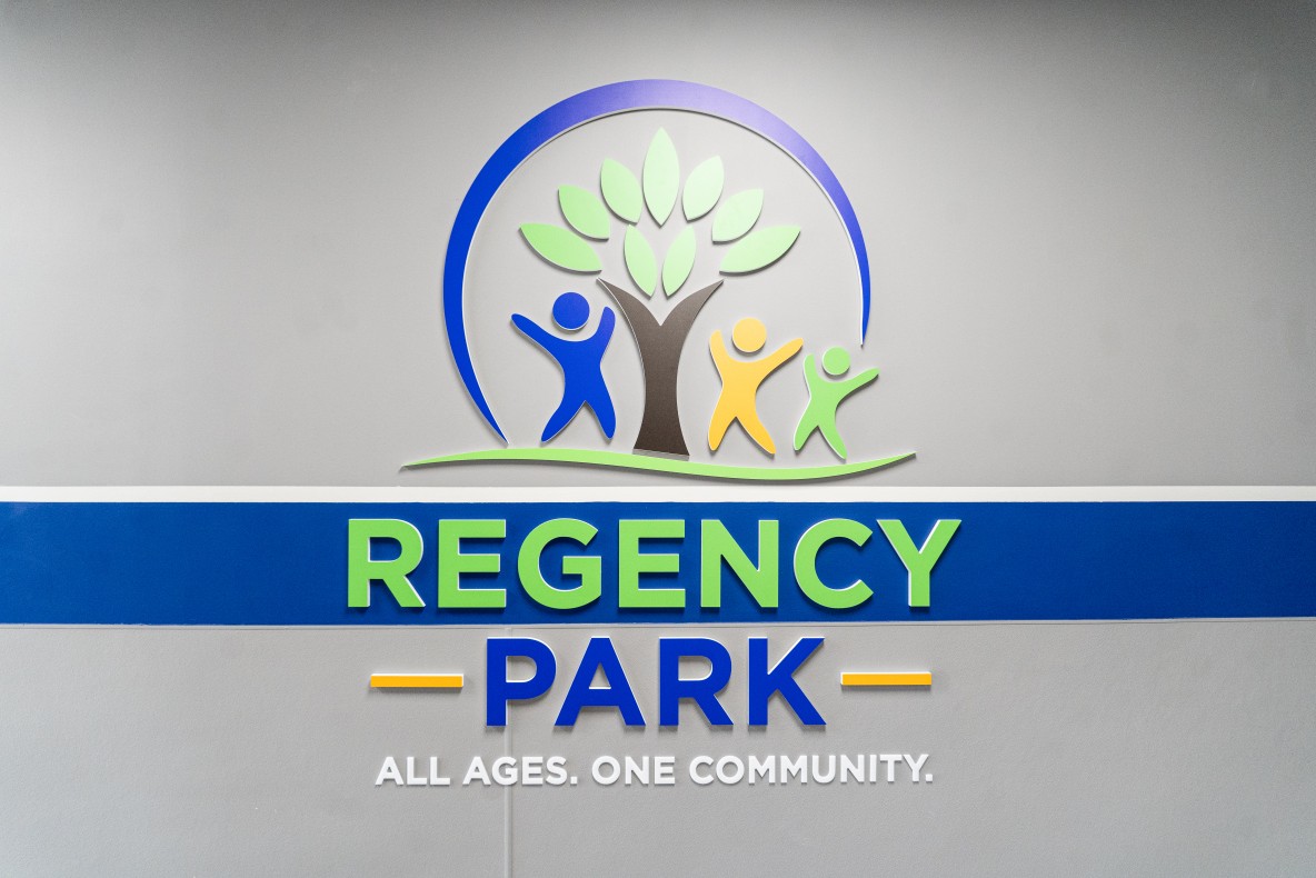 Custom blue, green, and brown sign of the Regency Park community center.