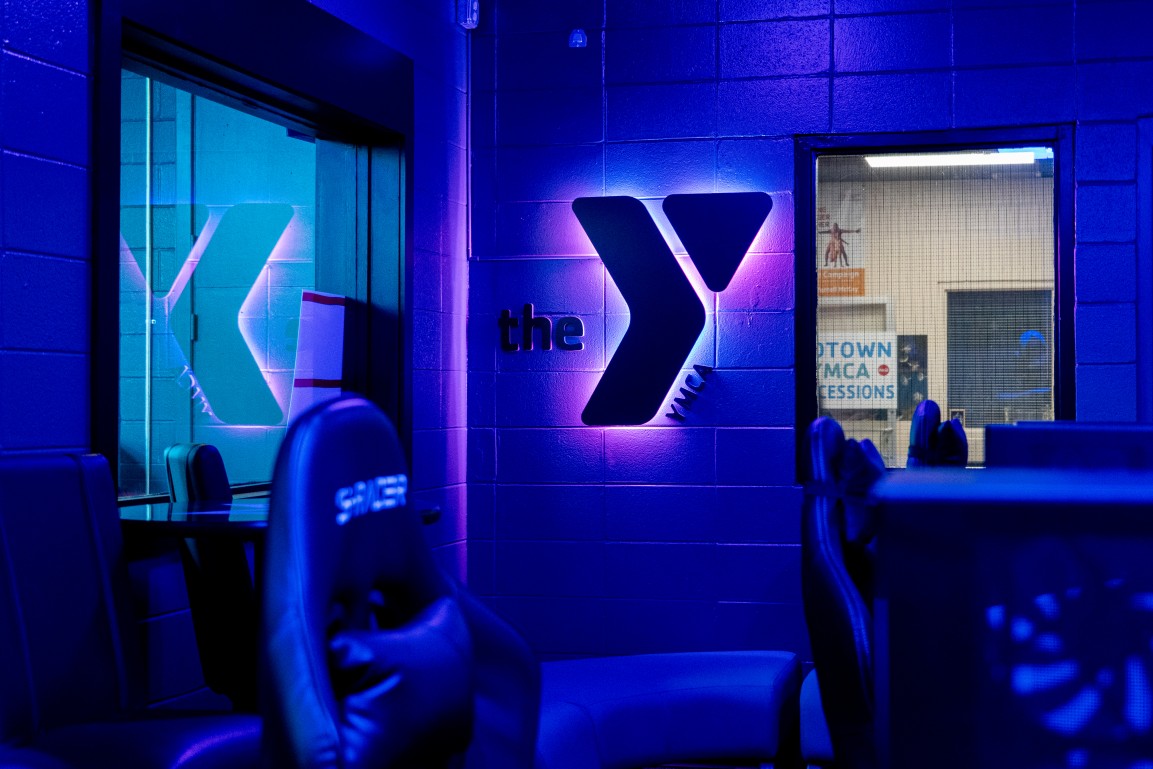 A colorful room with a backlit RGB YMCA logo sign.