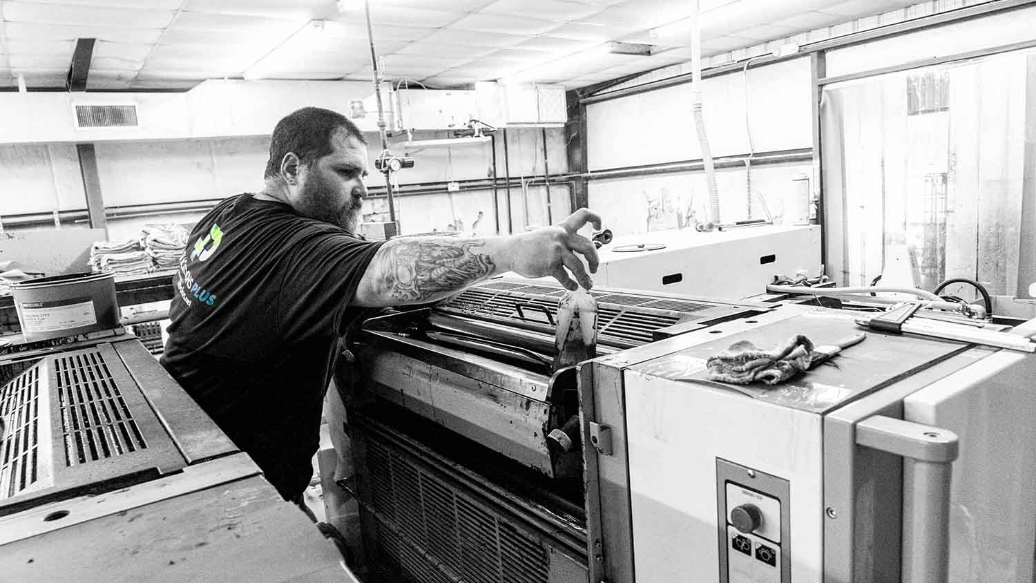 A man operating a large offset printer